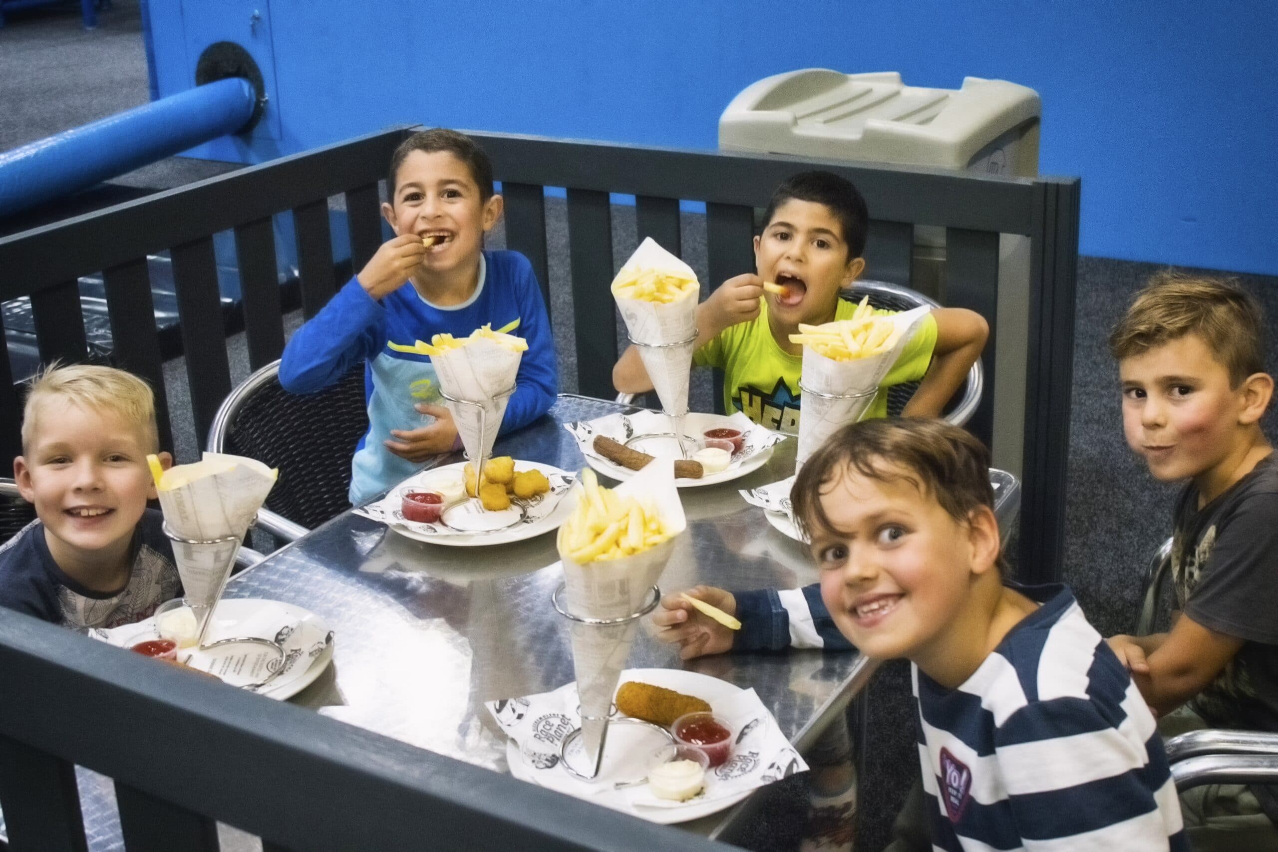 Kinderen eten lekkere patatjes na het spelen bij Jimmy's Speelparadijs.