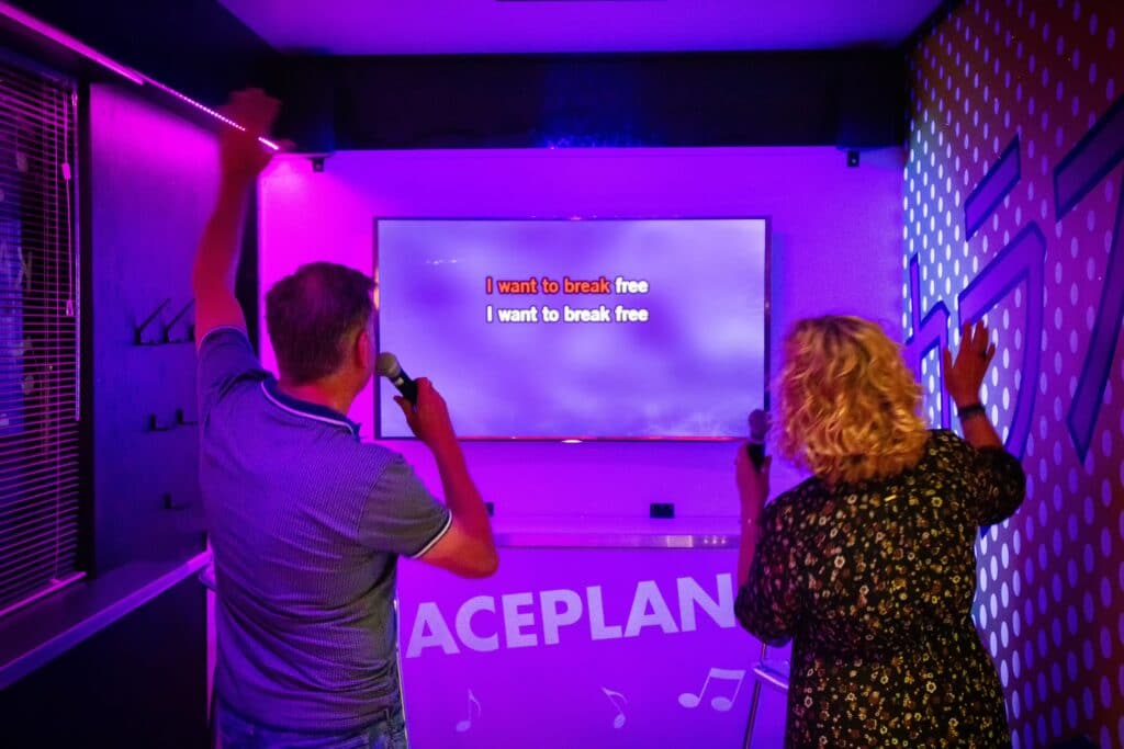 Twee zingende gasten in de karaokebar van Race Planet Amsterdam zingen hun favoriete karaoke lied tijdens een karaokesessie.