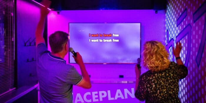 Twee zingende gasten in de karaokebar van Race Planet Amsterdam zingen hun favoriete karaoke lied tijdens een karaokesessie.