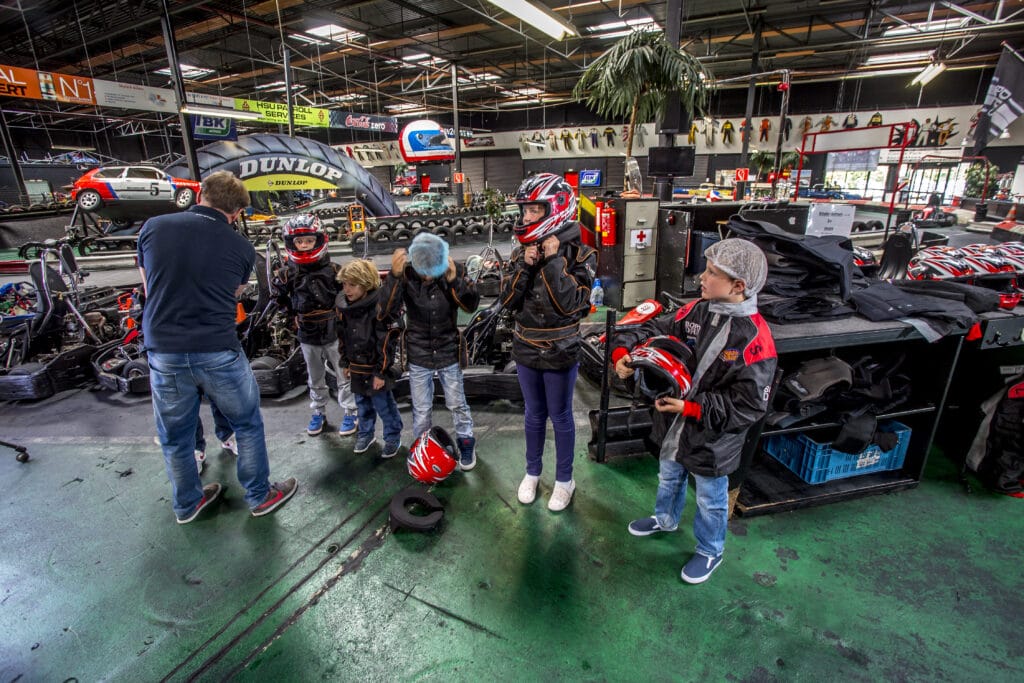 Kinderen kleden zich aan voor de kinderheat bij Race Planet op de kartbaan in Amsterdam en Delft.