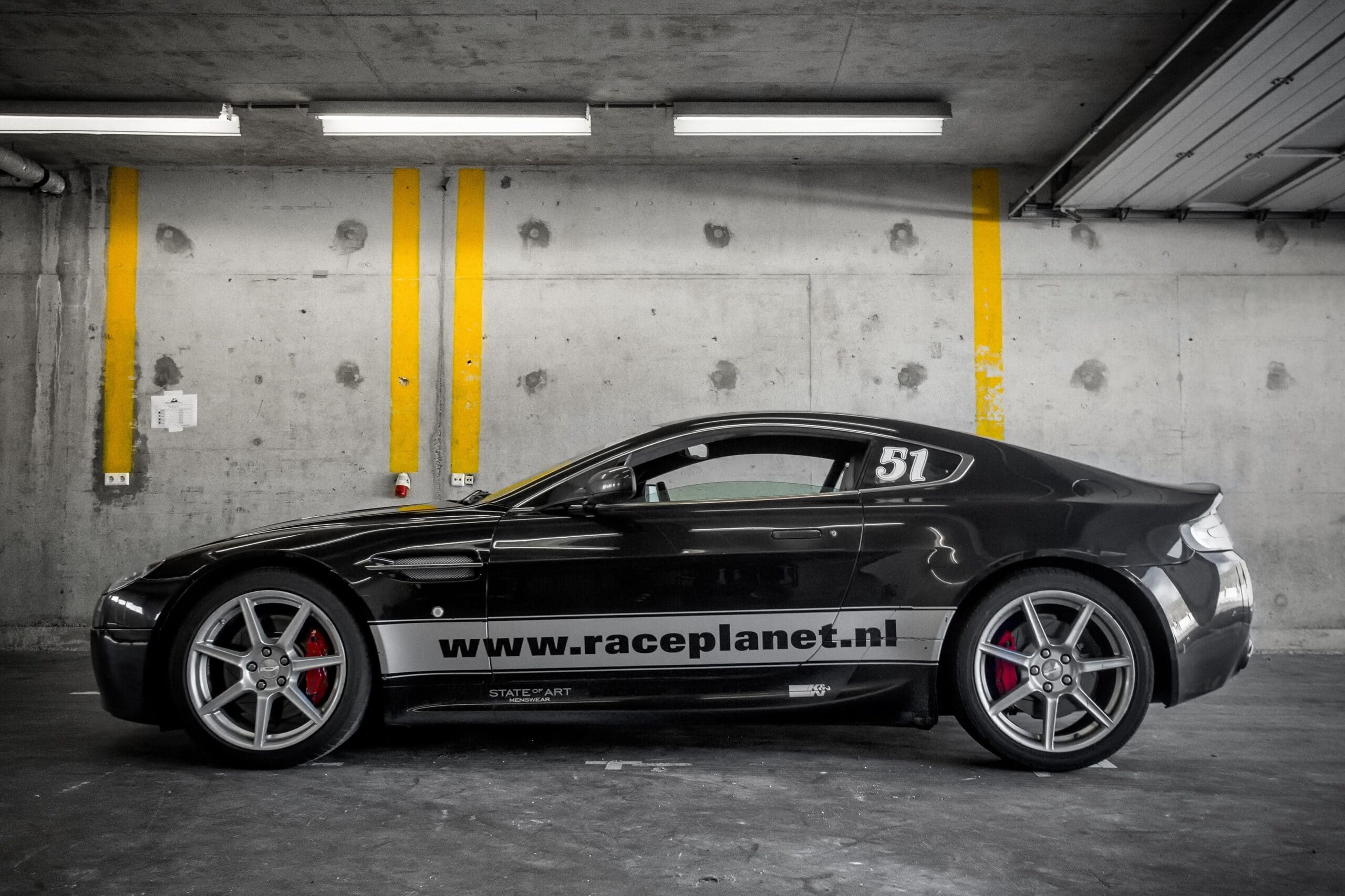 Zwarte Aston Martin V8 Vantage in een pitbox op Circuit Zandvoort tijdens een Bleekemolens Race Planet Race Experience