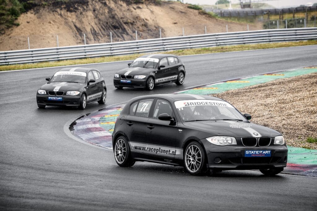 BMW 1-series op Circuit Zandvoort in de bocht, met deelnemers zelf achter het stuur tijdens een Race Experience van Race Planet