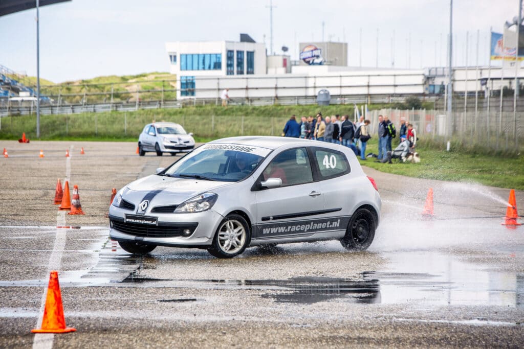 Renault Clio breekt uit in de bocht tijdens de slipproef op nat asfalt tijdens een Race Experience van Race Planet op Circuit Zandvoort.